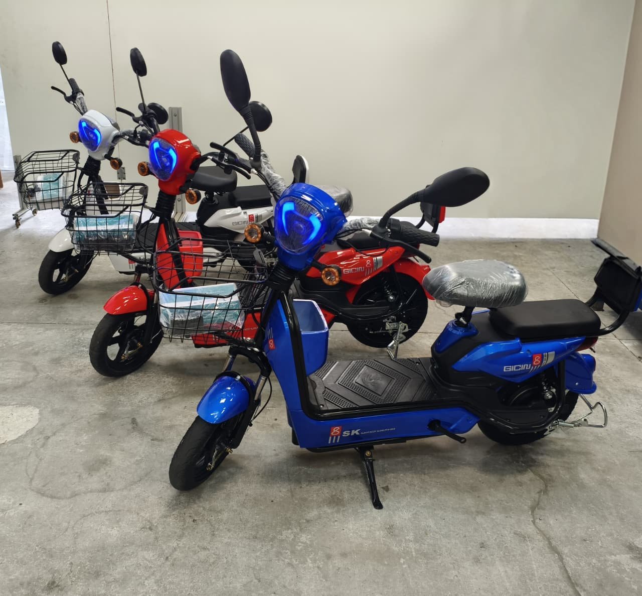 Moto Elétrica Gicin SK8 nas cores azul, vermelha e branca, estacionadas em um showroom da MyTech Imports em Curitiba.
